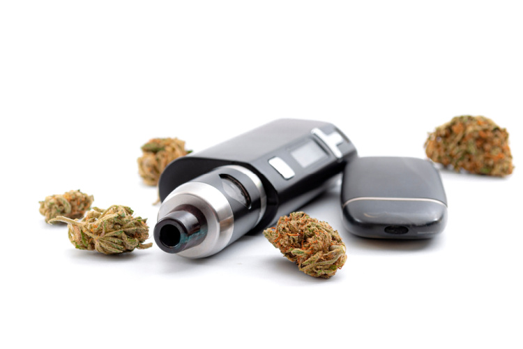 Cannabis vape pen with battery next to cannabis flower nugs